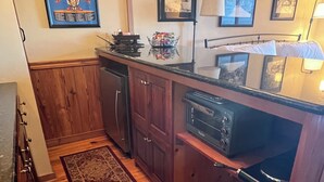 A kitchen with wooden cabinets, a microwave, a stove, and a rug. - First Floor Slopeside Ski-in / Ski-out at Wintergreen, steps from main lodge (Wintergreen Resort)