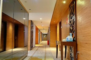 A hotel corridor with wooden walls, a glass door on the left, and a wooden counter on the right. - Longteng Hotel (Dehua)