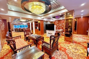 A hotel lobby with a chandelier, seating area, and a television screen. - Longteng Hotel (Dehua)
