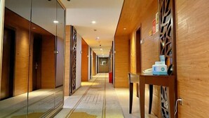 A hotel corridor with wooden walls, glass doors, and a patterned floor.