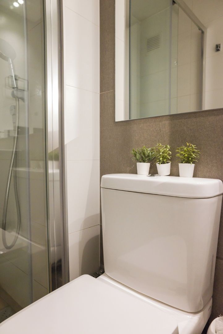 Une salle de bain moderne avec une douche à l’italienne en verre, des toilettes blanches et un miroir au-dessus du lavabo.