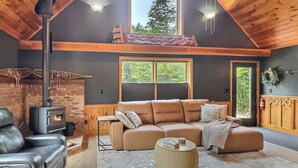 Una sala de estar acogedora con un sofá grande, una chimenea y un techo alto con vigas de madera.