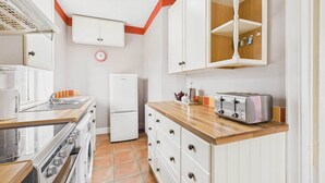 A kitchen with white cabinets, a wooden countertop, a stainless steel oven, a refrigerator, and a toaster. - Host Stay Highgarth (Seahouses)