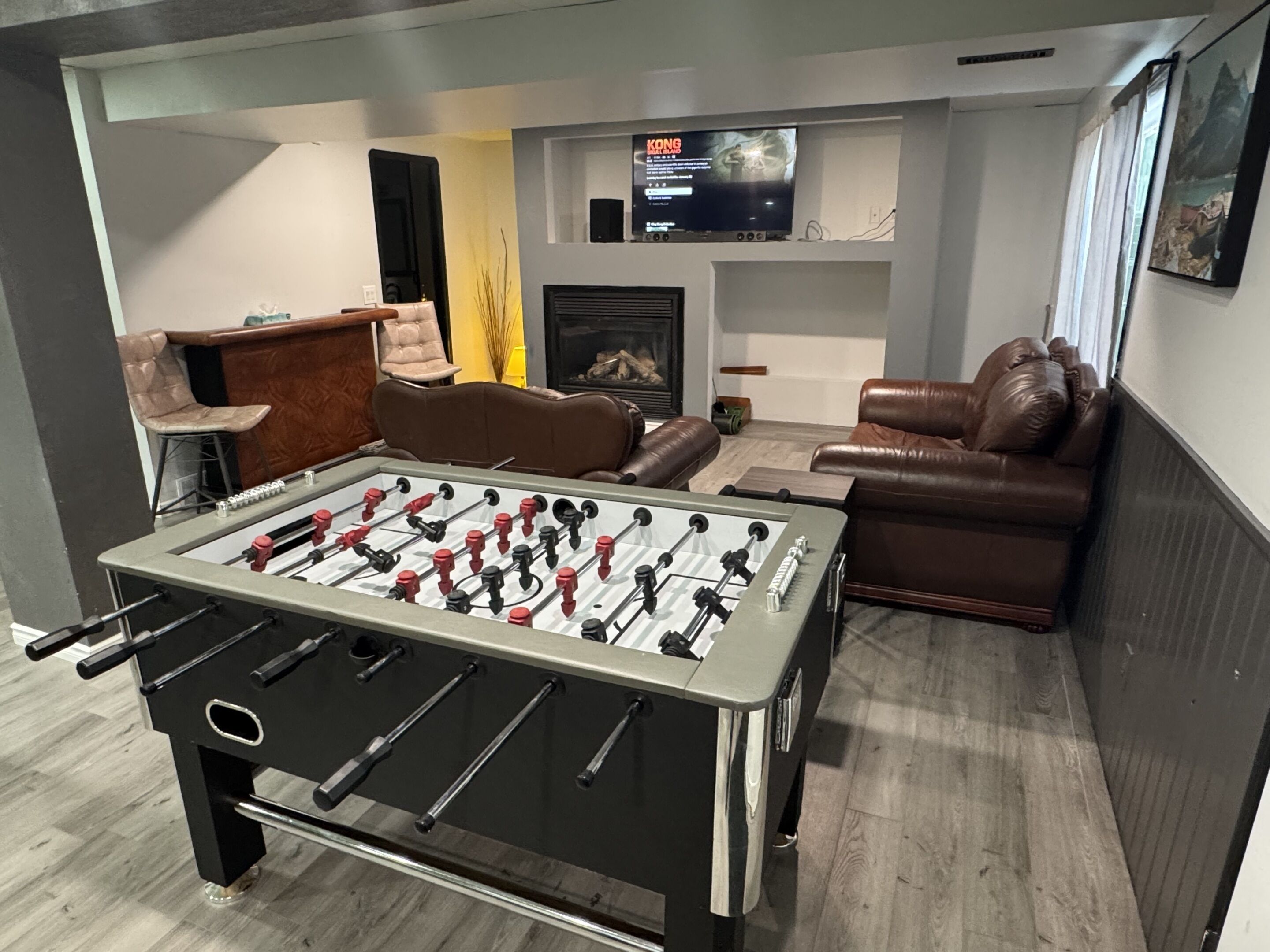A living room with a foosball table, a television, a fireplace, and leather sofas.
