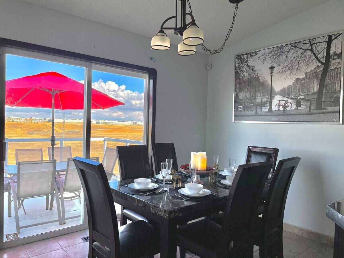 A dining area with a table set for four, a red umbrella outside, and a cityscape view through large windows.