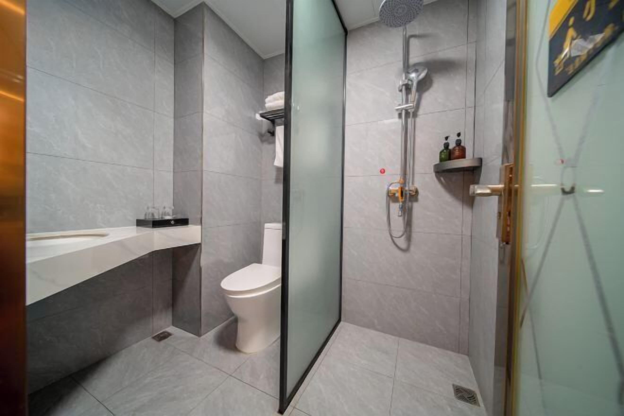 Een moderne badkamer met een douchecabine van glas, een wit toilet en een vloer van marmer.