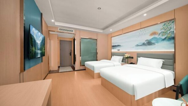 A hotel room with two beds, a desk, a TV, and artwork on the walls. - Anqing Yixin Hotel (Anqing)