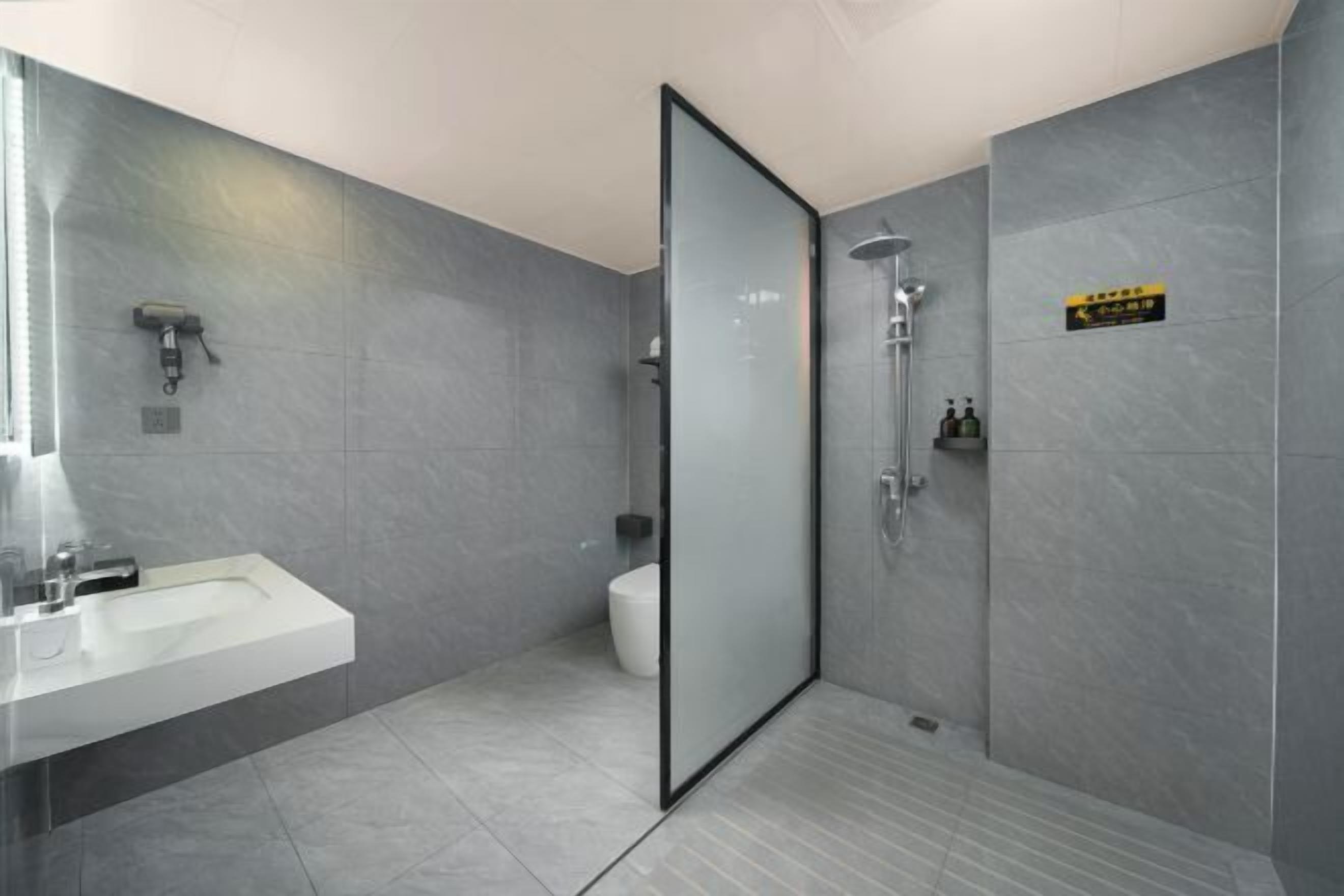 A modern bathroom with a glass shower enclosure, a white sink, and a toilet.