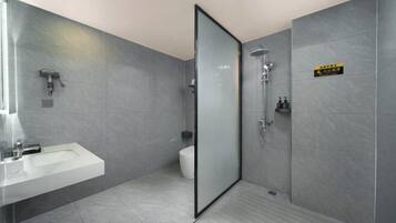 A modern bathroom with a glass shower enclosure, a white sink, and a toilet.
