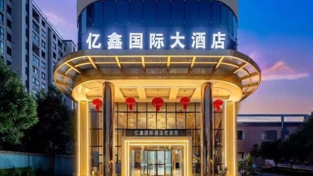A hotel entrance with a modern design, featuring a prominent sign and a circular structure with illuminated panels. - Anqing Yixin Hotel (Anqing)