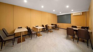 A conference room with multiple tables and chairs, a projector screen, and recessed ceiling lights. - Anqing Yixin Hotel (Anqing)