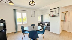 Een moderne woonkamer met een eethoek, een grijze bank en een boekenkast.