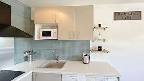 Eine moderne Küche mit weißen Schränken, einem Geschirrspüler von Bosch, einer Mikrowelle und einer Kaffeemaschine. Holzregale mit Dekorationselementen und ein Schild mit der Aufschrift 'Guy & Mital Lyon'.