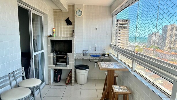 A small balcony with a kitchen area, a dining table, and a TV. - Apartment in Praia Grande - Gourmet balcony with sea view - Air conditioning - Parking space (Praia Grande)