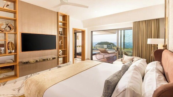Habitación de hotel con una cama grande, televisión, balcón con vistas y una estantería de madera con objetos decorativos.