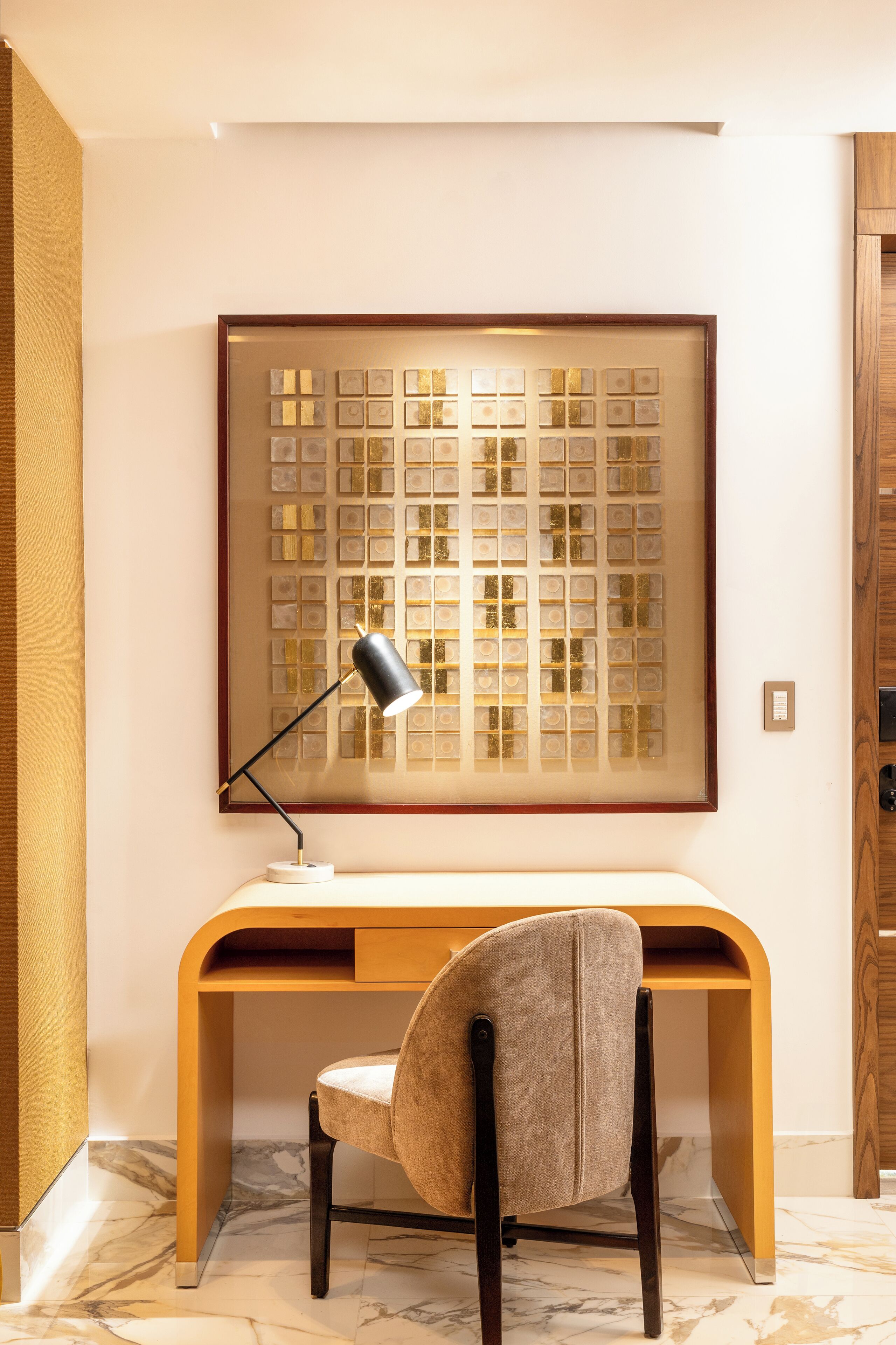 Un bureau moderne, avec une chaise, une lampe et un panneau décoratif au mur.