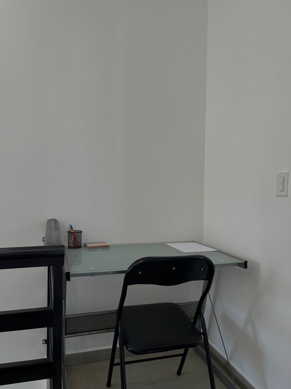 A small office space with a glass desk, a black chair, and a metal filing cabinet. - CASA RAMONA (Loreto)