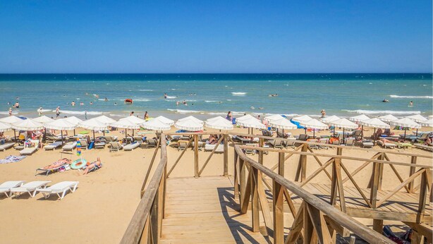 A wooden boardwalk leading to a beach with white umbrellas and sun loungers. - Gorgeous home in Rojales (Rojales)