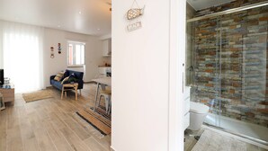 A modern living room with a sofa, a dining table, and a kitchen area. - Sea & Sun Apartment II (Nazaré)
