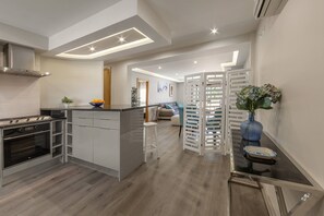 Une cuisine moderne dotée d’un îlot central, d’un four encastré et d’un coin repas avec une table et des chaises en verre.