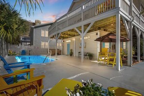 Ein Poolbereich mit überdachter Terrasse, Sitzgelegenheiten im Freien und Blick auf den Pool.