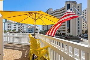 Ein Balkon mit einem gelben Sonnenschirm, einem gelben Stuhl und einer amerikanischen Flagge.