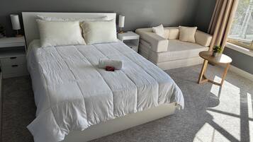 Un dormitorio moderno con una cama grande, una mesita de noche, una pequeña mesa redonda y un sofá.