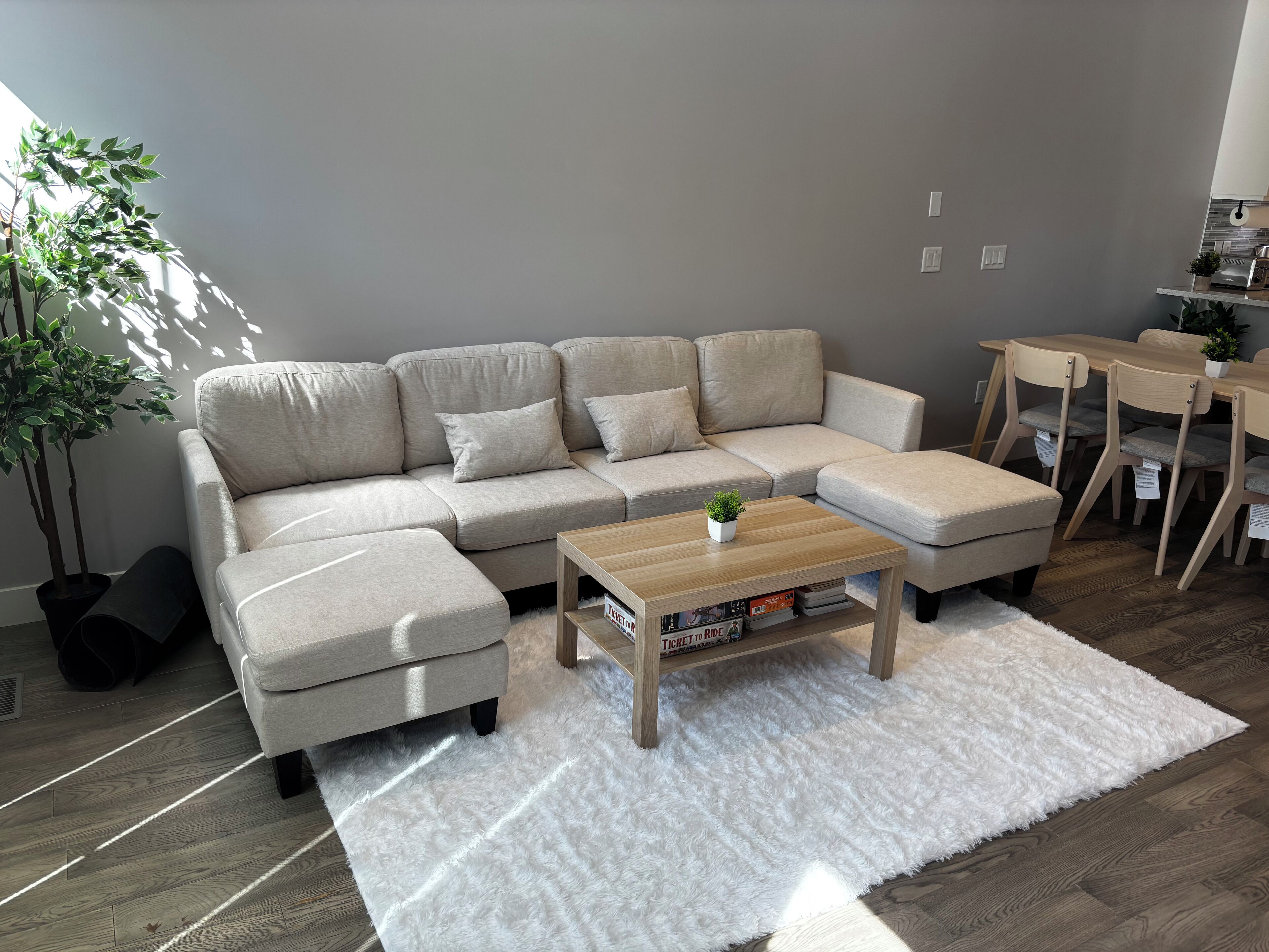 Een moderne woonkamer met een modulaire bank, een salontafel en een eethoek met stoelen.