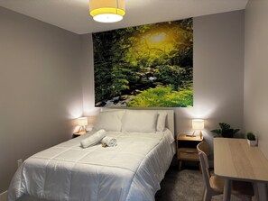 A bedroom with a bed, bedside lamps, a desk, and a chair.