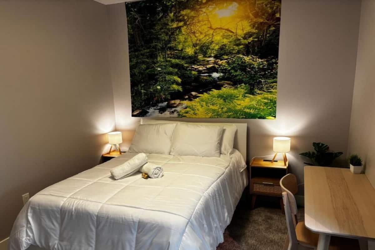 Un dormitorio con cama, lámparas de noche, una mesita y una silla.
