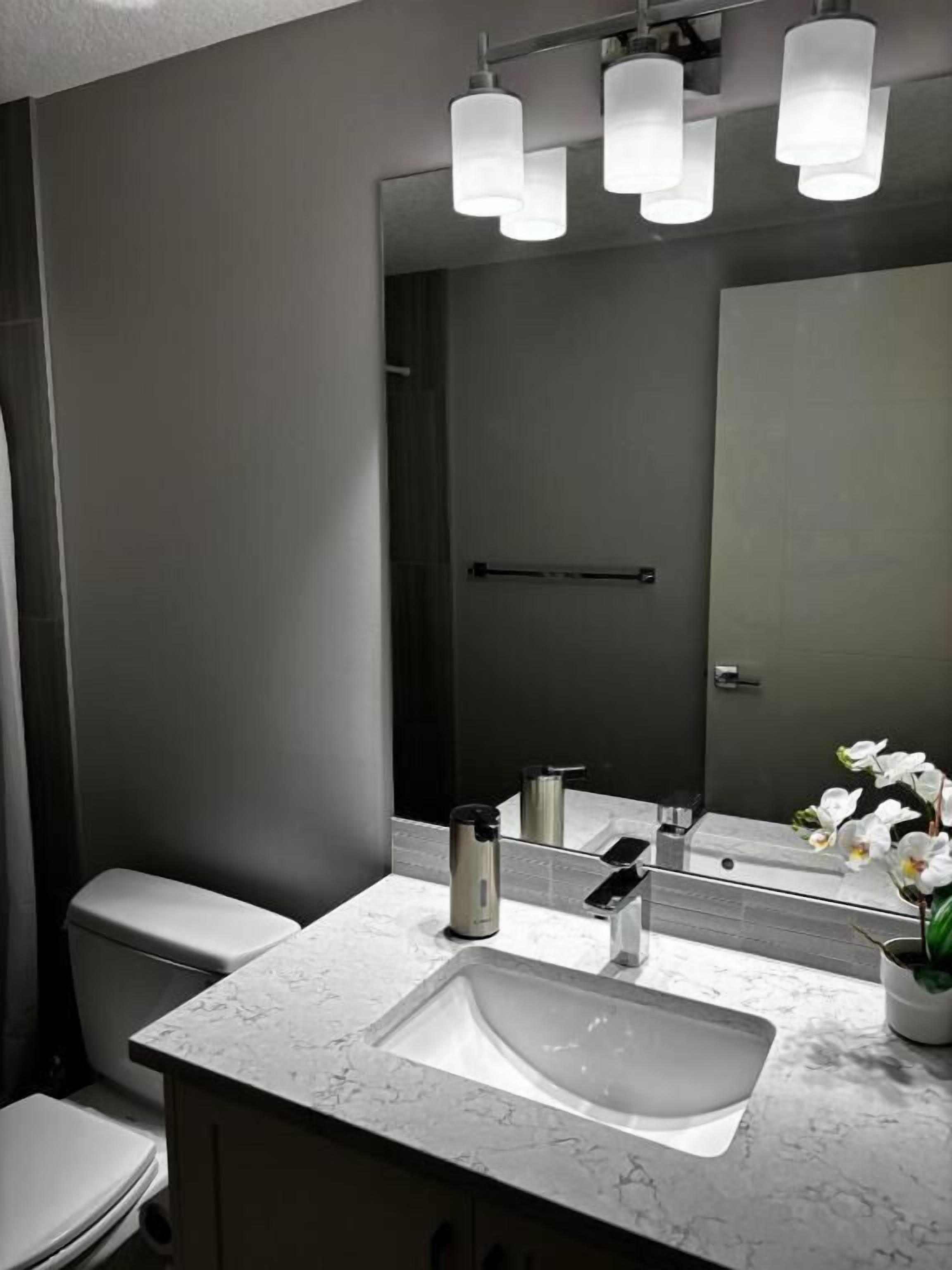 A bathroom with a white sink, a mirror, and a toilet.