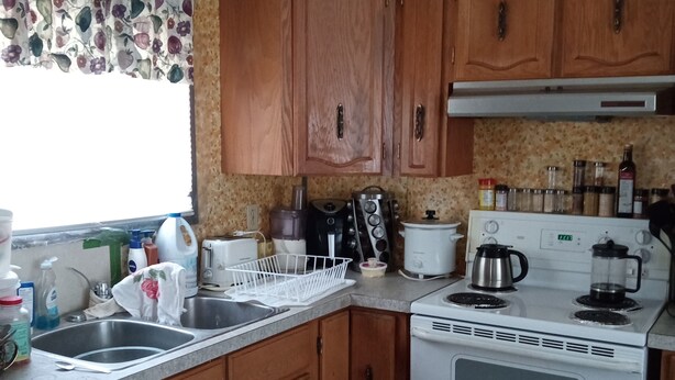 A compact kitchen with wooden cabinets, a white stove, and various kitchen appliances.