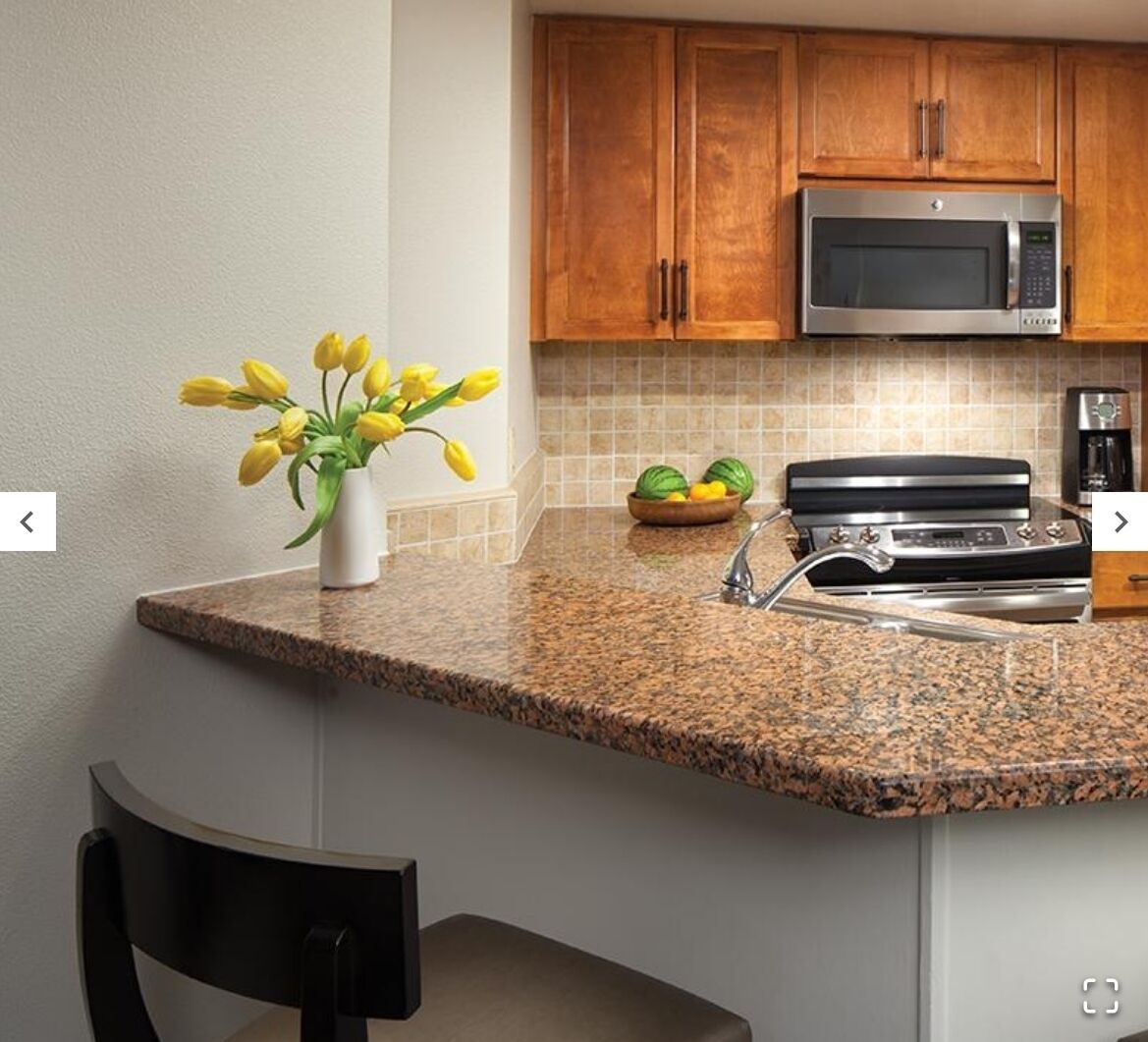 A kitchen with granite countertops, a stainless steel microwave, a gas stove, and wooden cabinets.