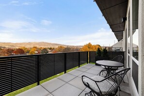 A balcony with a view of a hilly landscape, a black metal fence, and two round tables with chairs. - Private game room, fire pit, and hot tub overlooking the foothills +  just minutes from downtown Boise (Boise)
