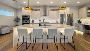 A modern kitchen with a central island, bar stools, stainless steel appliances, and pendant lighting. - Private game room, fire pit, and hot tub overlooking the foothills +  just minutes from downtown Boise (Boise)
