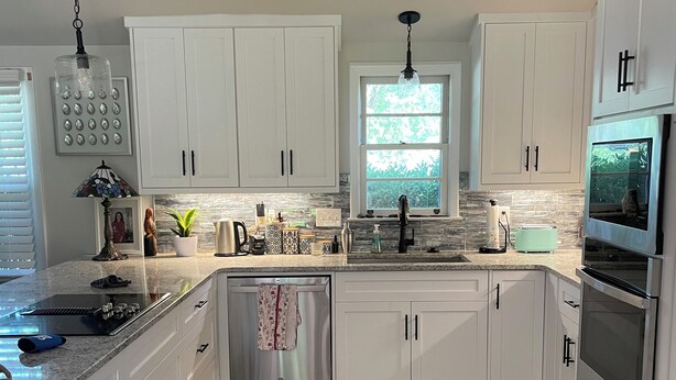 A modern kitchen with white cabinets, stainless steel appliances, a large window, and a wooden floor. - Charming Masters Cottage within a short walk <1 mile to the Augusta National. (Augusta)