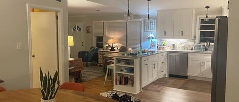 Una cocina moderna con armarios blancos, un comedor con mesa de madera y una isla de cocina.
