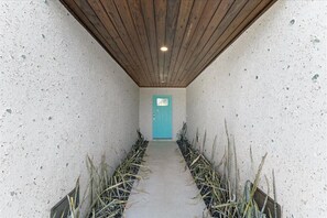 A narrow hallway with a wooden ceiling and a blue door at the end.