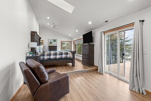 Ein Schlafzimmer mit Bett, Schreibtisch, Stuhl, Fernseher und einer Schiebetür zu einem Balkon.