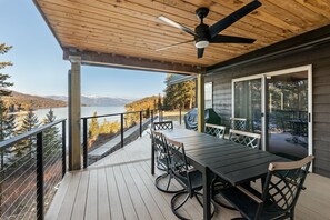 Eine Holzterrasse mit Tisch und Stühlen mit Blick auf einen See und Berge.