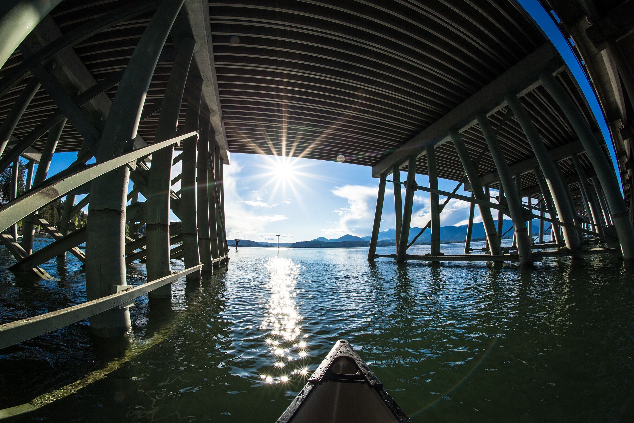 A boat under a bridge with a clear sky and mountains in the distance.