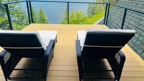 A deck with two lounge chairs facing a lake and mountains. - Bottle Bay View Lodge – 21-Acre Lakefront Retreat (Sagle)