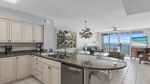 Een moderne keuken met een centraal eiland, een eetgedeelte met uitzicht en een balkon met een prachtig uitzicht op de oceaan.