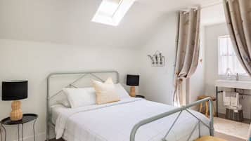 A modern bedroom with a bed, two bedside tables, a desk, and a window with curtains.