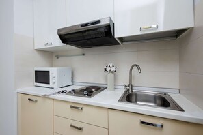 Een koelkast, een magnetron, een kookplaat, kookgerei, borden en bestek