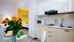 A modern kitchen with white cabinets, a microwave, and a stainless steel sink. - Studio Apartment --1 (Yerevan)