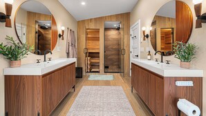 Ein modernes Badezimmer mit zwei Waschbecken, Holzvertäfelung, großen Spiegeln und einer Duschkabine aus Glas.