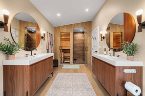 A modern bathroom with two sinks, wooden paneling, large mirrors, and a glass shower enclosure. - Riverside Hot Tub, Cedar Sauna & Arcade Games (Hunter)