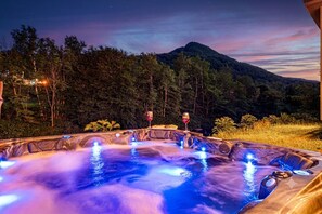 Ett bubbelbad med utsikt över bergen i skymningen.
