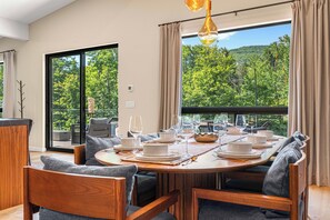 Ein Essbereich mit einem runden Tisch, gedeckt für sechs Personen, umgeben von Holzkästen mit grauen Kissen.